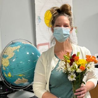  Teacher with flowers standing in front of globe